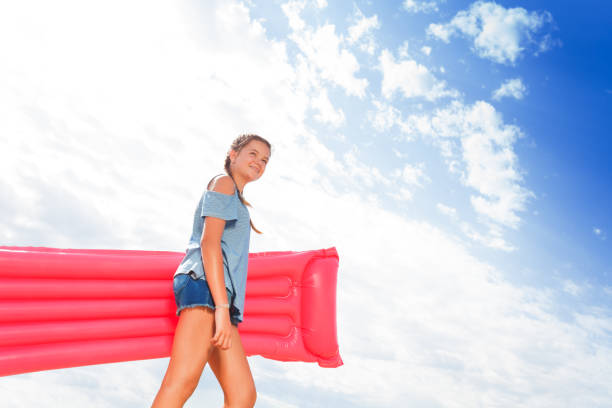 Girl walk with pink inflatable matrass to the sea Nice beautiful girl walk with pink inflatable matrass to the sea portrait over sky matrass stock pictures, royalty-free photos & images