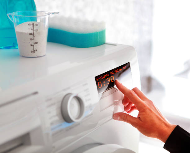 woman hand choosing program for washing machine stock photo