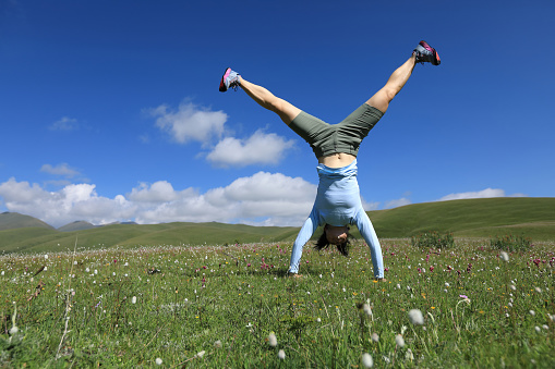 handstand woman have fun in a mountain peak meadow