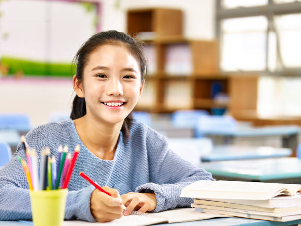portrait of an asian schoolgirl happy asian elementary school student studying in classroom looking at camera smiling, chinese ethnicity stock pictures, royalty-free photos & images