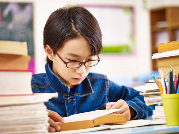asiatico scolaro lettura libro in classe - student effort book carrying foto e immagini stock
