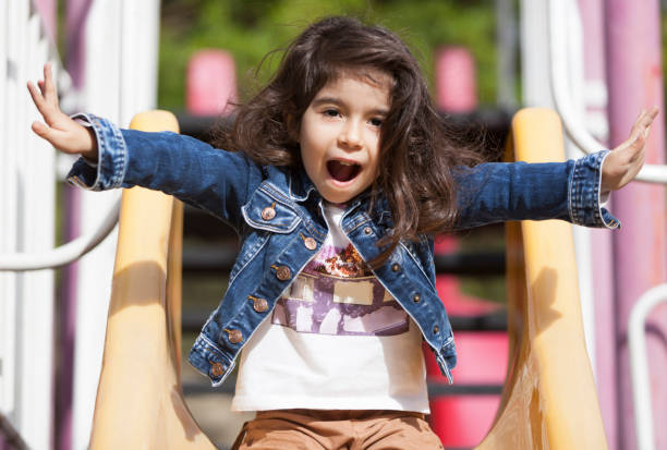 istock Cheerful little girl having fun while sliding at park on playground 859280814