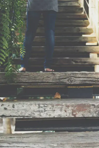 Photo of Wooden staircase of outdoor home vintage style design from natural material up to upstairs and fern green plant blur on leg step walking up on staircase