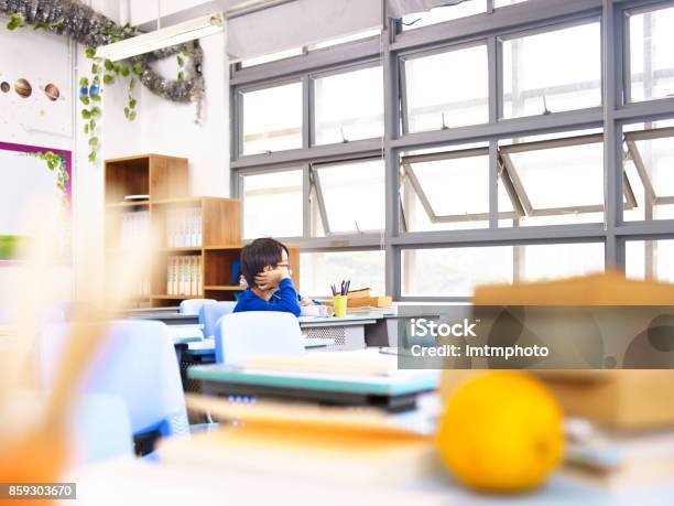 Asian Elementary School Student Sitting Alone In Classroom Stock Photo - Download Image Now