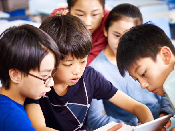istock asian elementary school children playing with digital tablet during break 859304010