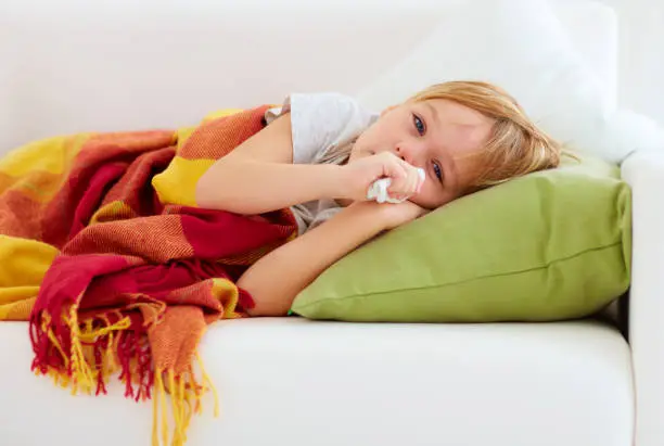 Photo of sick kid with runny nose and fever heat lying on couch at home