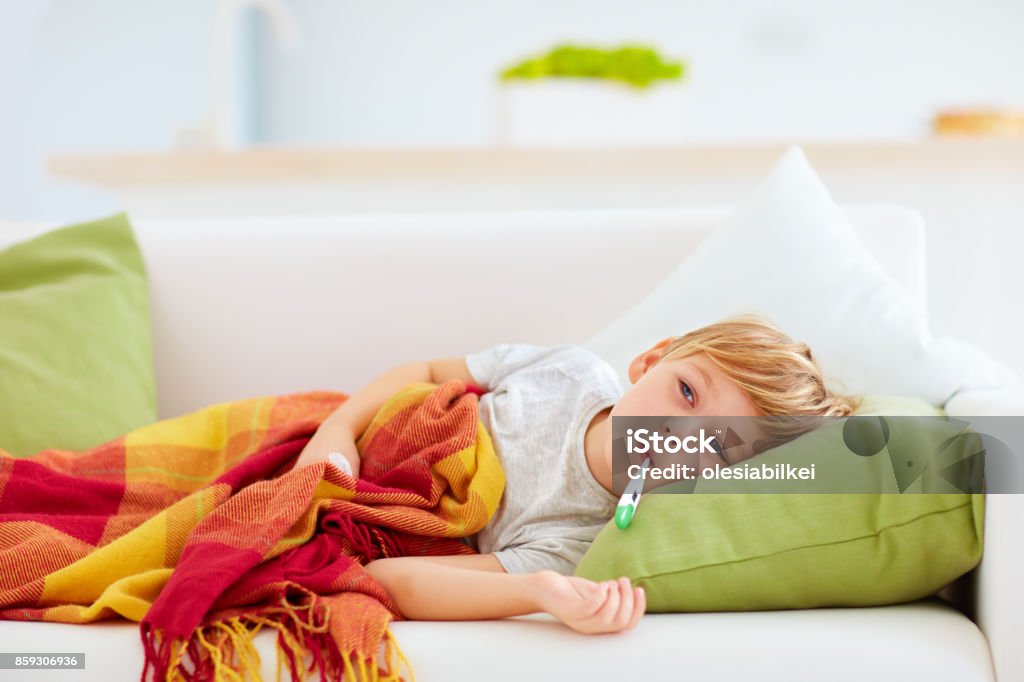 sick kid with runny nose and fever heat lying on couch at home Child Stock Photo