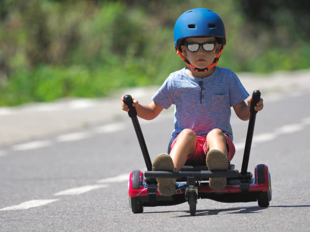 istock Happy boy standing on hoverboard or gyroscooter with kart accessory kit outdoor. New modern technologies 859310614
