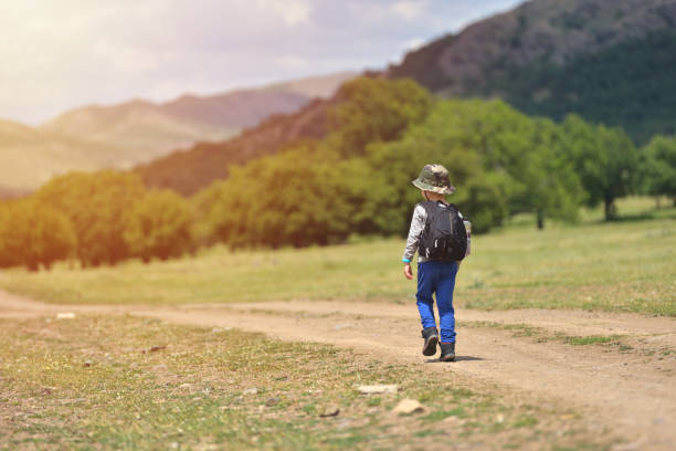 istock Cute child boy with backpack walking on a little path in mountains. Hiking kid 859310812