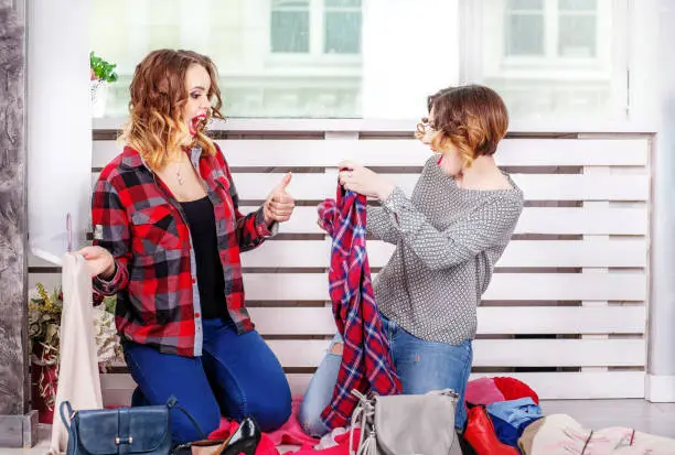 Two girls choosing clothes of her wardrobe. The concept of fashion, style, friendship.