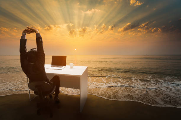 employees work during rest and relaxation imagine him sitting in the office. at the beach in the morning. - on beach laptop working imagens e fotografias de stock