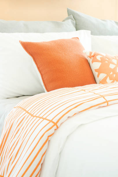 istock Closeup pillows on bed, orange and gray color scheme 859328250