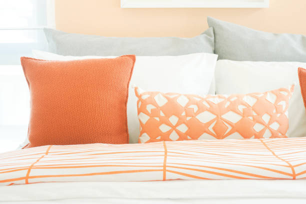 istock Closeup pillows on bed, orange and gray color scheme 859328302