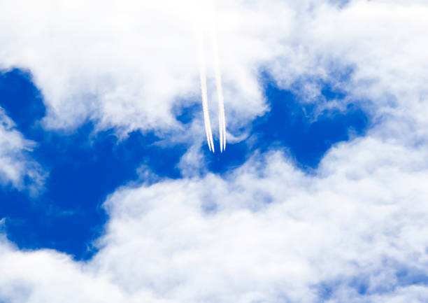 istock plane is flying high in blue skies cutting white clouds and leaves a trail 859329140