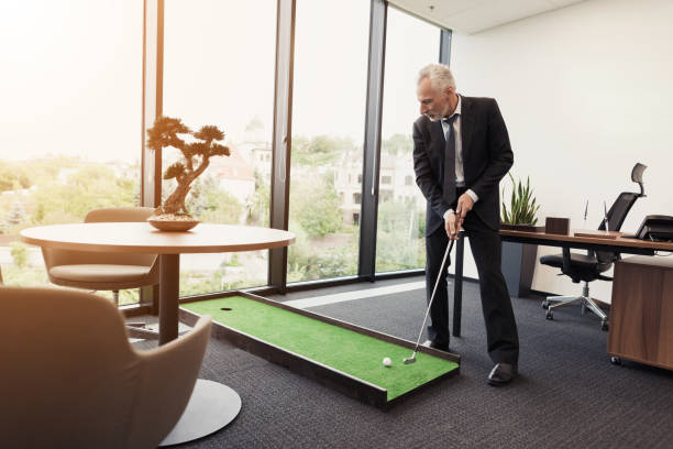 istock A man in a strict business suit plays in an office in a mini-golf 859329286