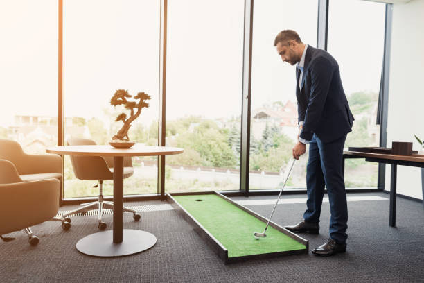 istock A man in a strict business suit plays in an office in a mini-golf 859329388