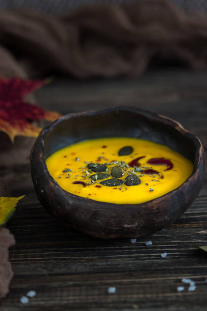 Homemade pumpkin cream soup with pumpkin seeds and pumpkin oil on a dark background
