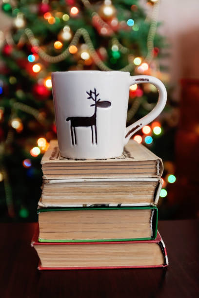 istock Christmas celebration with cup and gift box on books over bokeh and trees background 859336664
