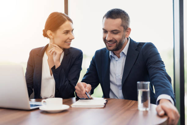 istock A man and a woman in strict business suits are discussing something while sitting at a table with a cup of coffee 859343698