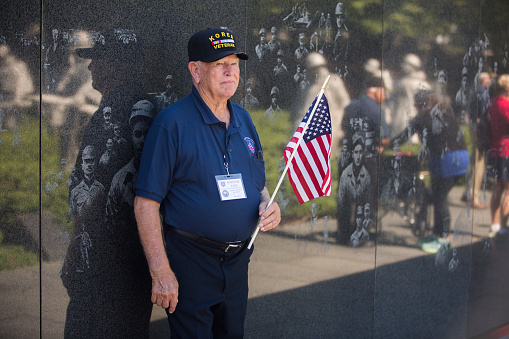 Korean War veteran holding the American Flag at a the Korean War Memorial in Washington District of Columbia