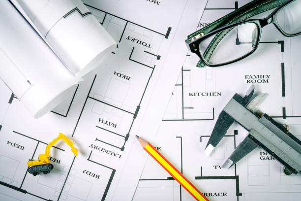 istock Top view of architect drawing on non identified architectural project with various of tools such as divider pencil eye glassed and small heavy equipment machine toys , toned color or instagram tone. 859347240