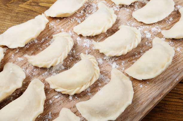 Raw Varenyky (Pierogi), Filled with Cheese Homemade raw dumplings (varenyky), filled with cheese on wooden cutting board - Traditional Slavic Food. pierogi stock pictures, royalty-free photos & images