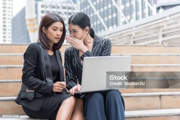Business Women Gossip While Using Laptop At Outdoor Business And Coworker Concept Stock Photo - Download Image Now