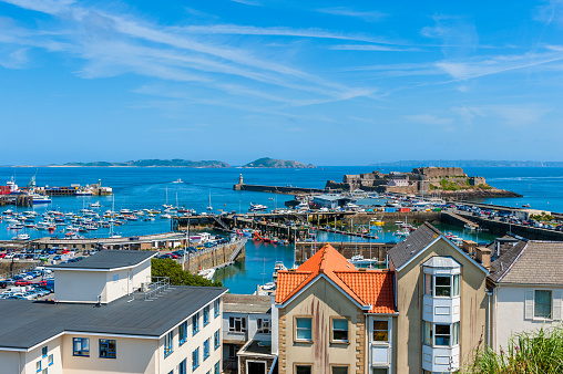High angle view over Harbor of Saint Peter Port, Guernsey, Channel Islands, UK. The Islands of Herm and Sark are visible in the distance.