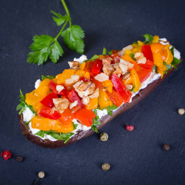 istock Baked eggplants stuffed with vegetable, walnut and cream cheese on a black slate background, close up 859368044