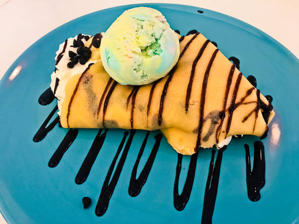 Cold crepe with chocolate, vanilla ice-cream and mousse on dish.
