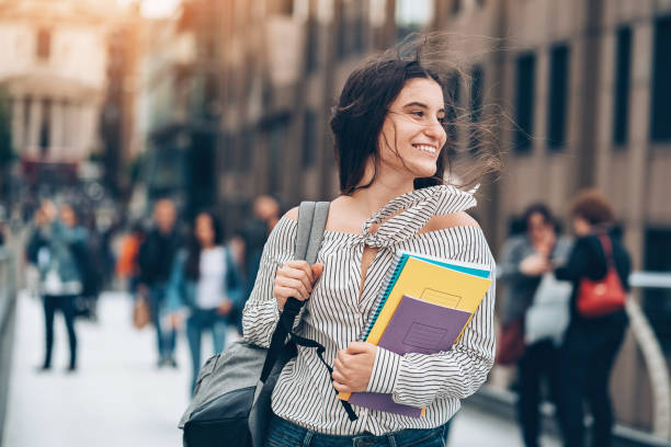 Smiling student walking at the wind Smiling student walking on the street adult education book stock pictures, royalty-free photos & images