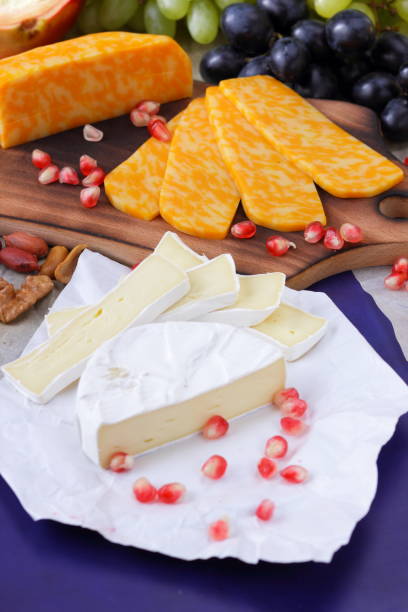 istock Camembert cheese, marbled cheese, orange cheese, different cheeses, dark blue grapes, red pomegranate, green grapes, peanuts and walnuts on a wooden board with an empty place for writing in retro style 859375068