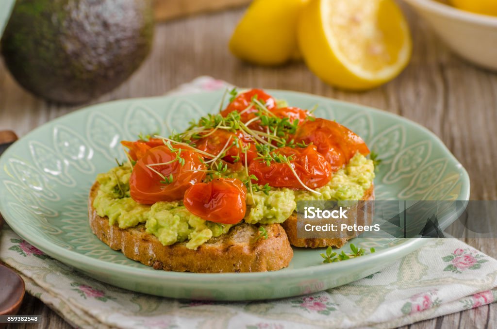 Avocado spread with tomatoes Avocado spread with tomatoes, roasted tomatoes and herbs on top Appetizer Stock Photo