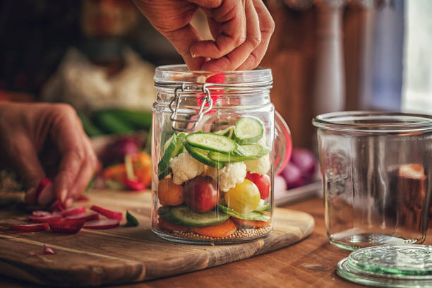 Preserving organic mixed vegetables in jars like carrots, cucumbers, tomatoes and cauliflower
