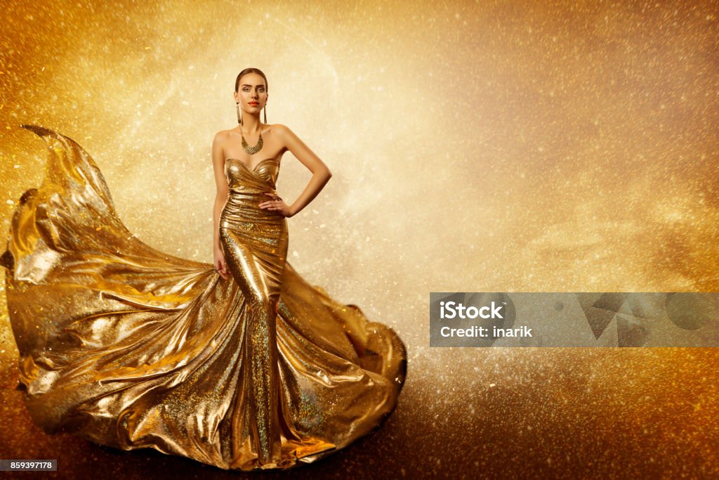 Modella di moda dorata, elegante donna che vola abito d'oro, tessuto abito scintillante agitando - Foto stock royalty-free di Dorato - Colore descrittivo