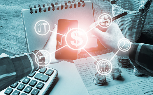 Hand holding smart phone with electronic pen and office tools, calculator,book bank,stack of coins, with business icons for finance management concept.