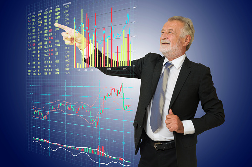 BusinessMan point his hand to Digital Stock Market information board including buy, sell, bid, offer, volume, Bargraph, Linegraph and Candlestick Graph.