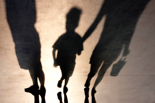 Blurry shadow of two person and a kid Blurry shadows of mother walking with son hand in hand and a man standing next to them lost stock pictures, royalty-free photos & images