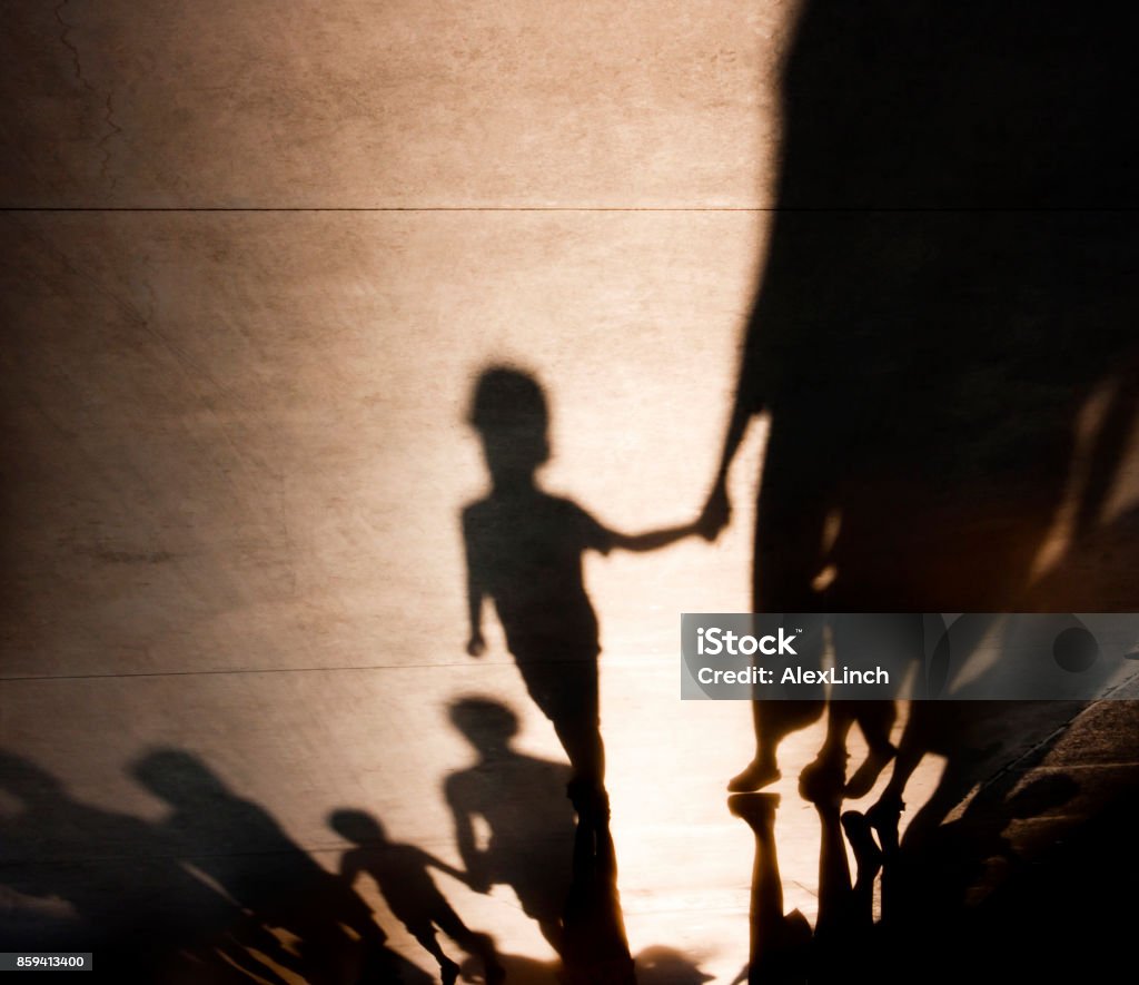 Blurry shadows of families with kids walking Blurry shadows silhouettes of families with kids  walking and holding hands on misty summer promenade Shadow Stock Photo