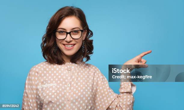 Smiling Brunette Girl Pointing Away Stock Photo - Download Image Now - Eyeglasses, Pointing, People