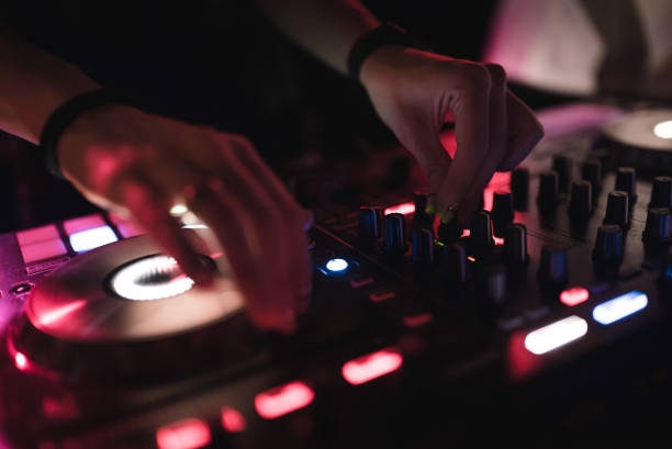 istock Hands of woman DJ tweak various track controls on dj's deck at night club 859414522