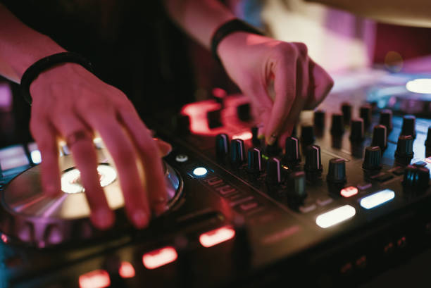 istock Hands of woman DJ tweak various track controls on dj's deck at night club 859414524