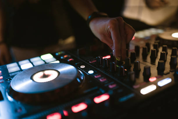 istock Hands of woman DJ tweak various track controls on dj's deck at night club 859414528