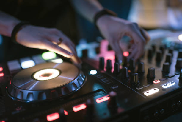 istock Hands of woman DJ tweak various track controls on dj's deck at night club 859417080