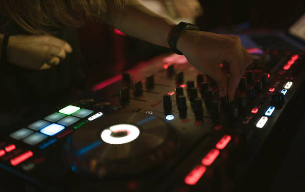 istock Hands of woman DJ tweak various track controls on dj's deck at night club 859417082