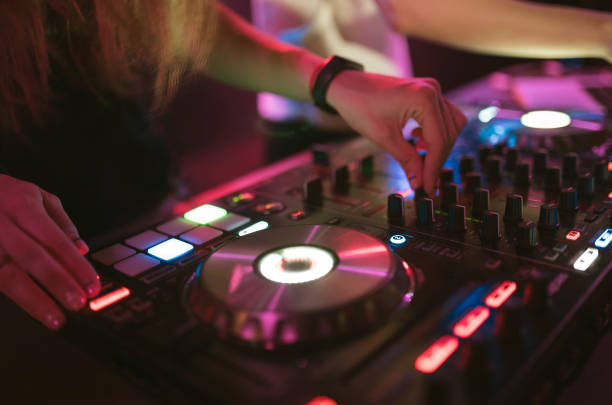 istock Hands of woman DJ tweak various track controls on dj's deck at night club 859417108