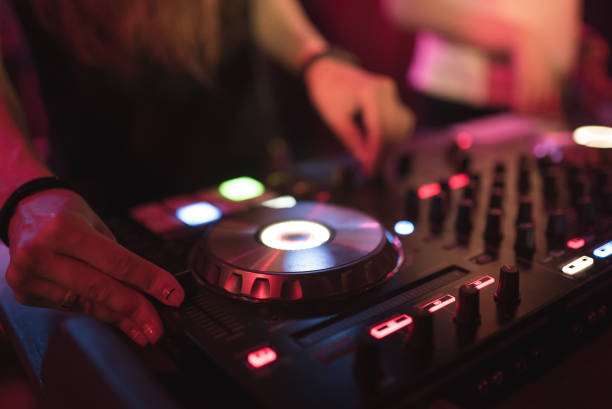 istock Hands of woman DJ tweak various track controls on dj's deck at night club 859417128