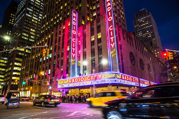 New York City, New York, USA - September 28, 2017: View of Radio City Music Hall in Manhattan seen at night with lights, cars, taxi's and Harry Styles on marquee.