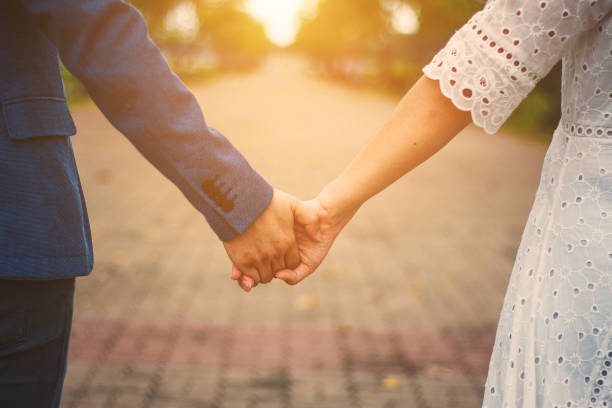 istock couple holding hands with sunlight  in park 859430370