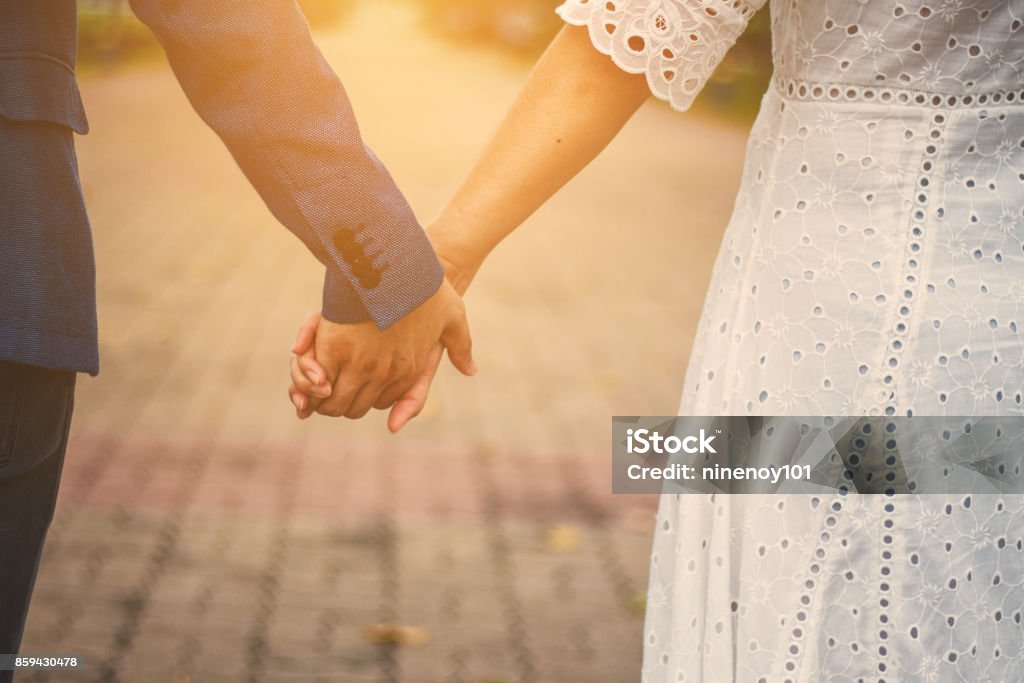 couple, main dans la main avec la lumière du soleil dans le parc - Photo de Tomber amoureux libre de droits